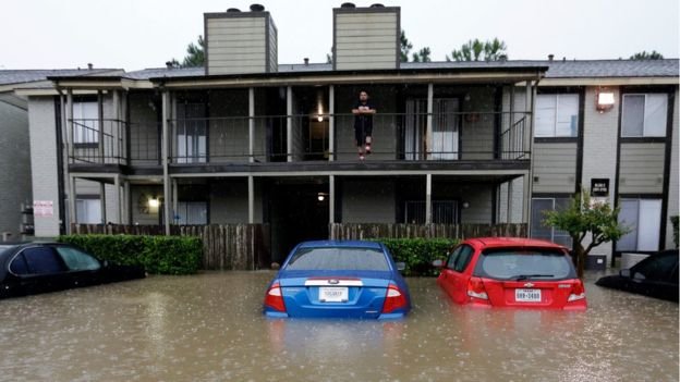 Một người dân đứng trên tầng hai nhìn nước lũ bao vây khu chung cư của mình hôm 18-4 - Ảnh: AP