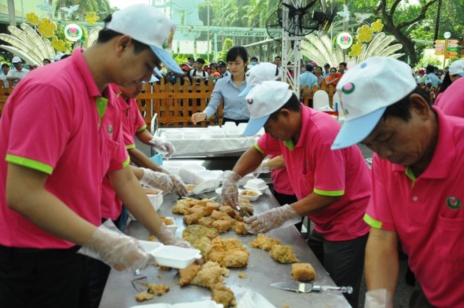 Nhân viên công viên văn hóa Đầm Sen dùng tay chia nhỏ bánh chưng cho người dân - Ảnh: Hồng Lam
