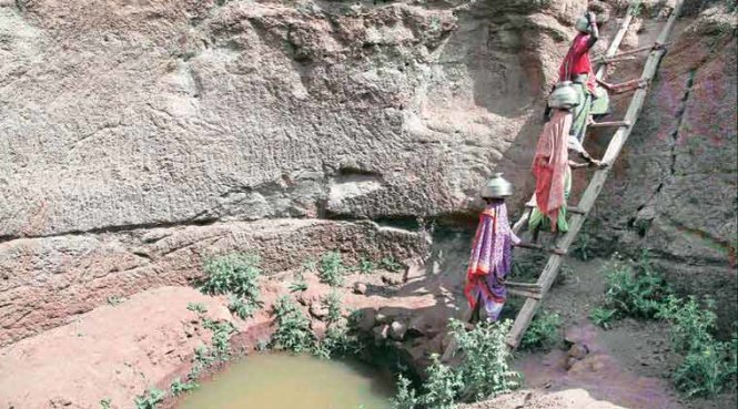 Phụ nữ lấy nước từ một cái giếng gần cạn nước tại một ngôi làng ở Surgana Taluka, gần Nasik, Ấn Độ - Ảnh: PTI