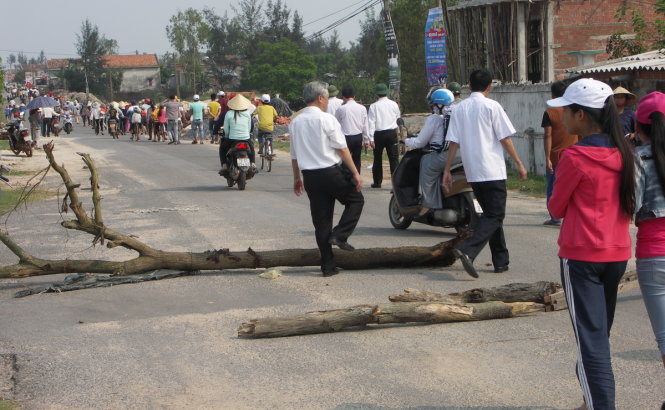 Người dân Hải Ninh đổ ra đường và dùng cả cột điện chặn đường không cho xe đưa đại biểu tới nơi làm lễ khởi công - Ảnh: LG