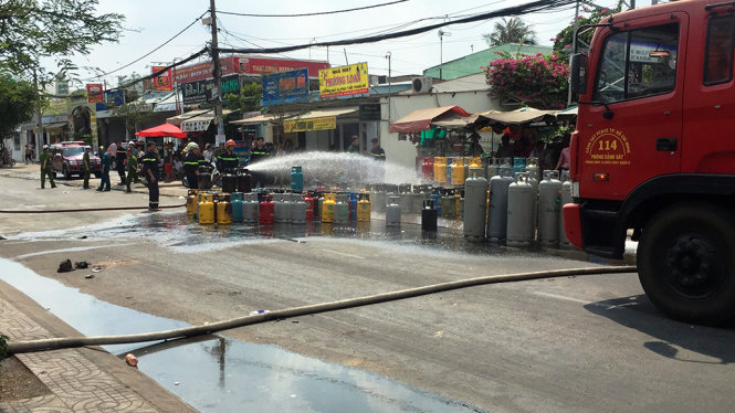 Cảnh sát xịt nước vào các bình gas đã được đưa ra ngoài - Ảnh: Ngọc Khải