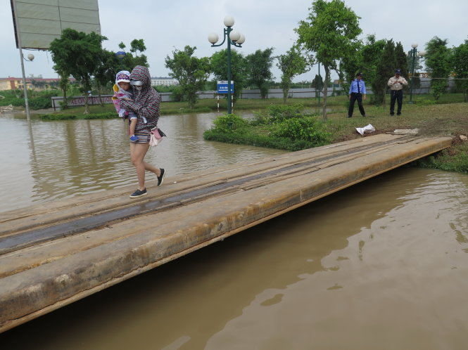 Đến chiều 27-5, người dân ở tòa nhà HH2 - khu chung cư Spark Dương Nội (Q.Hà Đông, Hà Nội) vẫn còn phải đi qua cầu tạm do nước ngập bủa vây từ trận mưa ngày 25-5 - Ảnh: Quang Thế