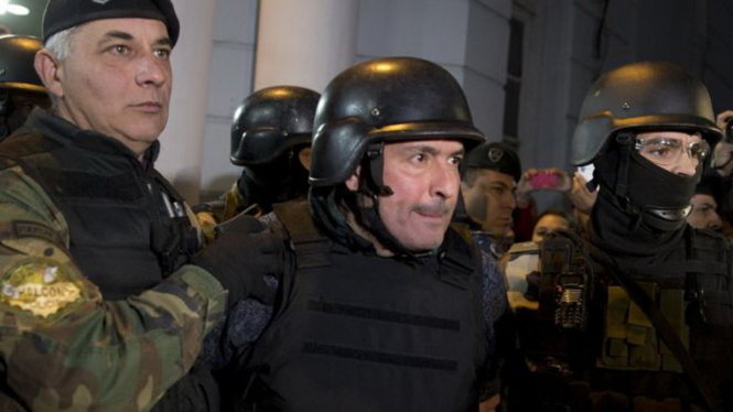 Ông Lopez (ở giữa) được cho mặc áo giáp và mũ chống đạn để bảo đảm an toàn tính mạng trước khi bị dẫn giải ra ngoài trụ sở cảnh sát - Ảnh: AP