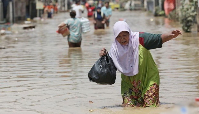 Một phụ nữ Indonesia đi qua con đường ngập nước ở Bekasi, ngoại ô Jakarta, Indonesia - Ảnh: AP