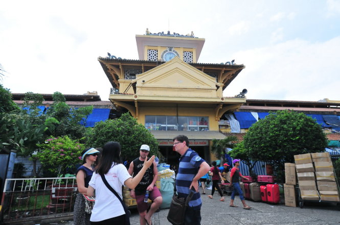 Du khách nước ngoài được hướng dẫn viên người Việt giới thiệu về kiến trúc và nét văn hóa của chợ Bình Tây, Q.6, TP.HCM - Ảnh: Hữu Thuận