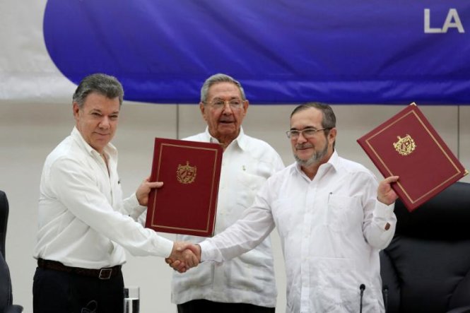 Tổng thống Colombia (trái) bắt tay thủ lĩnh FARC sau khi ký thỏa thuận ngừng bắn dưới sự chứng kiến của Chủ tịch Cuba - Ảnh: Reuters