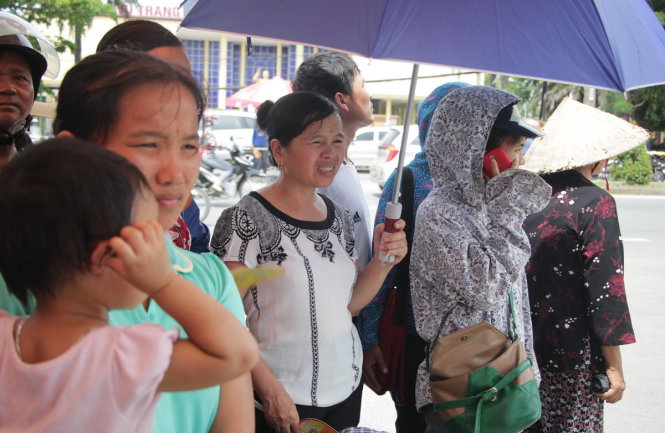 Một phụ huynh ở Nghệ An che dù đợi con dưới nắng gắt - Ảnh: DOÃN HÒA