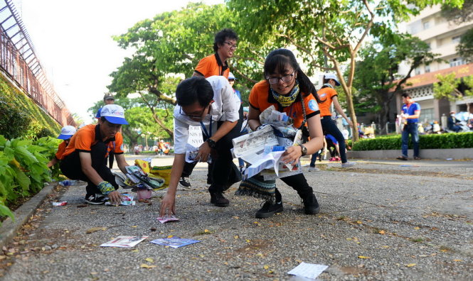 Các bạn tình nguyện viên nhặt rác, tờ rơi và giấy báo sau khi kết thúc môn thi Anh văn chiều 1-7 trên đường Nguyễn Văn Cừ, Q.5, TP.HCM - Ảnh: HỮU KHOA