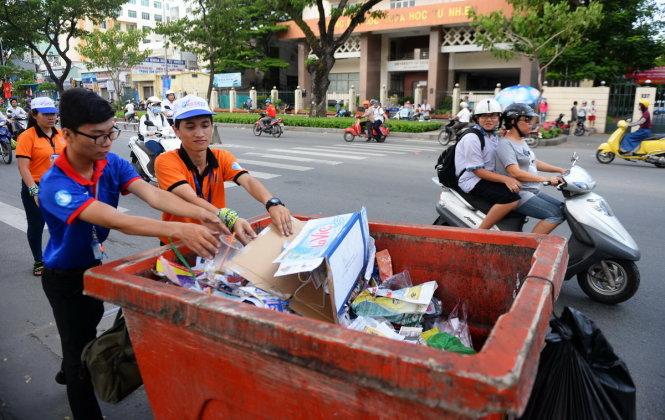 Tình nguyện viên thu gom rác, tờ rơi và giấy báo trên đường Nguyễn Văn Cừ, Q.5, TP.HCM - Ảnh: HỮU KHOA