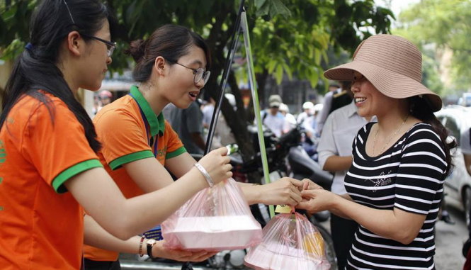 Các tình nguyện viên CLB Cơm 5000 Hà Nội trao suất cơm miễn phí cho một sĩ tử tại điểm thi trường ĐH Y Hà Nội - Ảnh: CHÍ TUỆ
