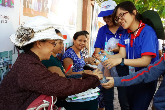 Tình nguyện viên tươi cười mời phụ huynh uống nước miễn phí tại điểm thi Trường Song ngữ Lạc Hồng (TP Biên Hòa, Đồng Nai) - Ảnh: A LỘC