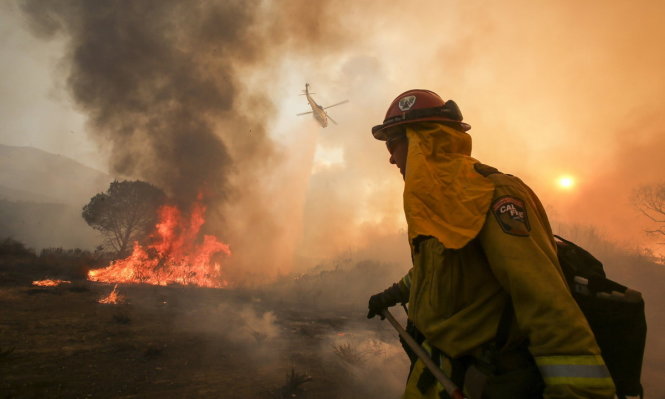 Lính cứu hỏa và trực thăng chữa cháy đang ra sức dập tắt đám cháy ở Santa Clarita - Ảnh: AP