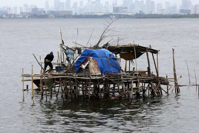 Một ngư dân Philippines đang gia cố căn chòi của mình tại một ngôi làng ven biển ở thị trấn Bacoor, phía nam Manila, hôm 31-7 khi bão Nida sắp đến gần - Ảnh: EPA