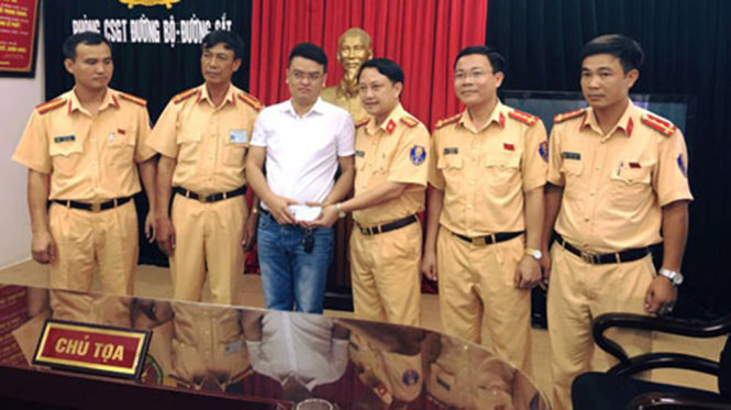 Lãnh đạo Phòng CSGT đường bộ, đường sắt Công an Thanh Hóa trao trả số tiền CSGT nhặt được cho anh Phạm Văn Cường - Ảnh do CATH cung cấp.