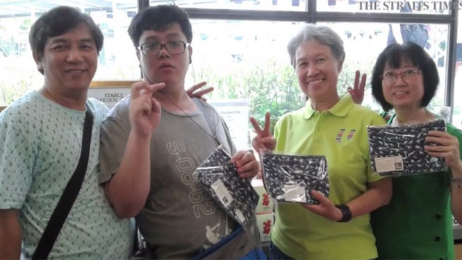 Bà Hà Tinh (thứ hai từ phải) trong chương trình bán hàng gây quỹ do Trung tâm tiềm lực người tự kỷ tổ chức. Bà đã mua bóp với thiết kế của See Toh Sheng Jie (thứ hai từ trái) - Ảnh: STRAITSTIMES