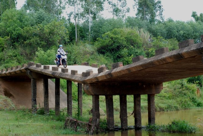 Cầu Nam Trạch mới chưa thể đưa vào sử dụng do hết vốn giữa chừng nên người dân và phương tiện phải nín thở khi qua cây cầu cũ đã  xuống cấp – ảnh: Quốc Nam