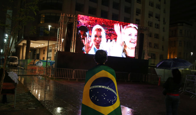 Một người Brazil khoác lên vai quốc kỳ xem lễ bế mạc thông qua màn hình lớn ở trung tâm Thành phố Rio de Janeiro.