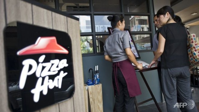 Một nhân viên cửa hàng Pizza Hut tại Myanmar chào món với khách hàng - Ảnh: AFP