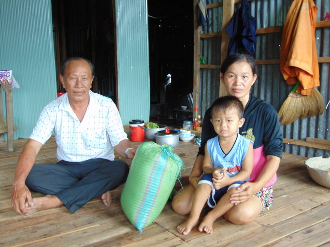 Ông Nguyễn Văn Thum, tổ trưởng “tổ thuê đất làm từ thiện”, đi phát gạo cho một hộ nghèo - Ảnh: NG.NGỌC
