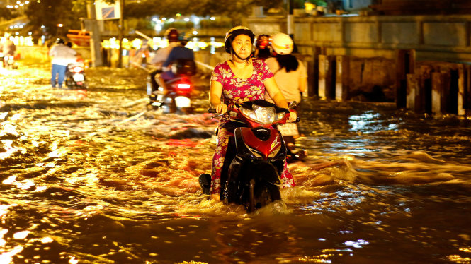 Một người phụ nữ cố gắng chạy xe qua dòng nước tại đường Bình Đông (Q, 8, TP.HCM)  - Ảnh: NGỌC DƯƠNG