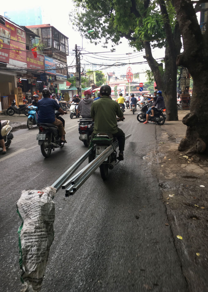 Một chiếc xe máy kẹp hai bó sắt dài, di chuyển như một vũ khí sát thương trên đường La Thành, Hà Nội  - Ảnh: Việt Dũng