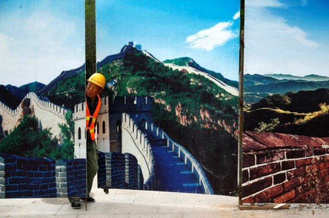 Một công nhân nhìn qua hàng rào một khu công trường xây dựng được trang trí bằng các hình ảnh của Vạn lý trường thành tại Bát Đạt Lĩnh, phía bắc Bắc Kinh, Trung Quốc - Ảnh: Reuters