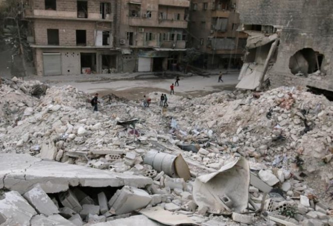 Người dân đi trên đống đổ nát của các tòa nhà nằm trong khu vực al-Kalaseh do lực lượng nổi dậy kiểm soát tại thành phố Aleppo, Syria - Ảnh: Reuters