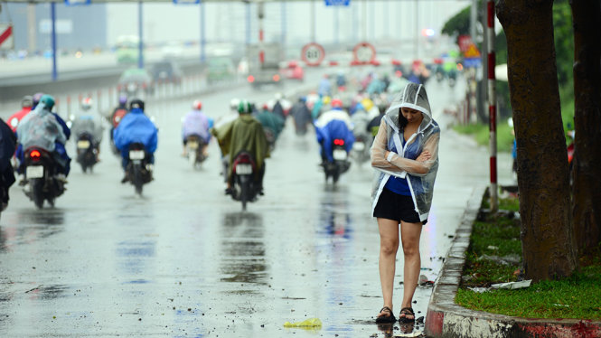 Một cô gái đứng đón xe dưới mưa - Ảnh: Lê Phan
