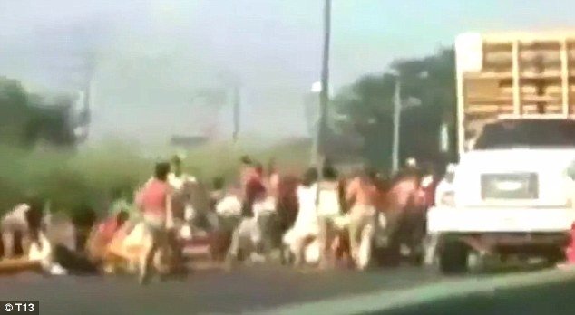 Hình cảnh cắt ra từ đoạn video cho thấy người dân đổ xô vào chiếc xe tải bị chặn lại để bắt gà - Ảnh: Daily Mail