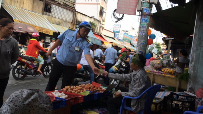 Nhân viên tổ QLTTĐT P.Bình Hưng Hòa A (Q.Bình Tân) thu 150.000 đồng tiền “lấn chiếm lề đường” của một người bán trứng trên lề đường Gò Xoài sáng 30-9 - Ảnh: HOÀNG LỘC