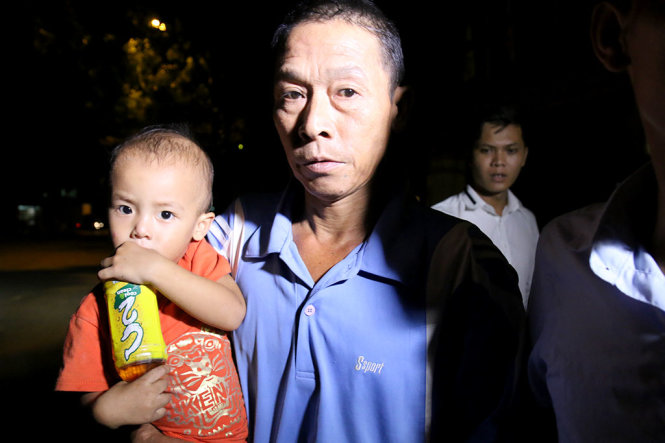 Ông Thạch ôm đứa cháu nội khi bước ra khỏi trụ sở công an quận Hoàng Mai - Ảnh: HOÀI NAM