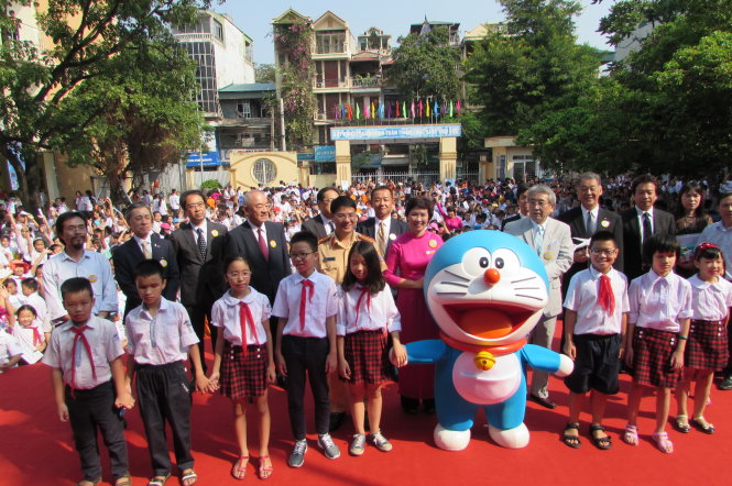 Đại diện phía Nhật Bản và Trường PTCS Nguyễn Đình Chiểu cùng các em học sinh chụp hình lưu niệm với chú mèo máy Doraemon - Ảnh: HÀ THANH