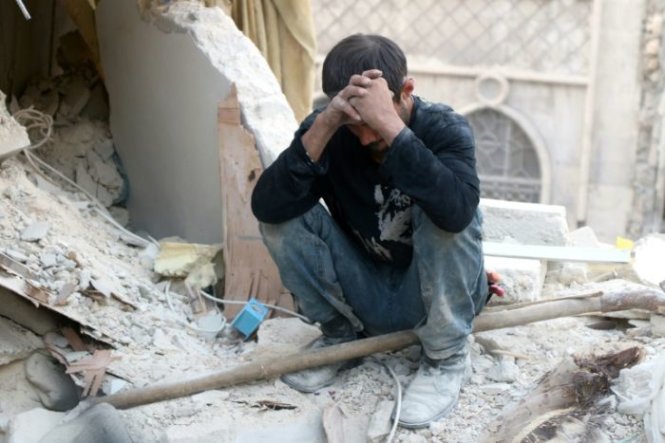 Thị trưởng thành phố Aleppo nói rằng thế giới đang bỏ quên thành phố đang bị tàn sát này. Trong ảnh là một người dân Syria ngồi ôm đầu bên đống đổ nát của các tòa nhà - Ảnh: PBS