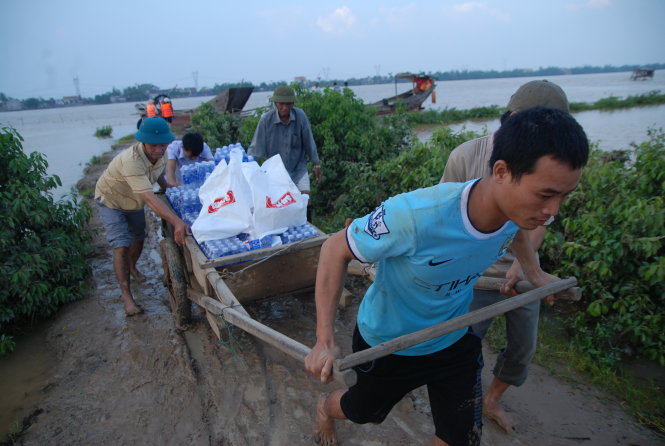 Người dân vùng Cồn Nâm, cồn nổi nằm tách biệt giữa sông Gianh (thị xã Ba Đồn, Quảng Bình), mang xe kéo ra mép sông kéo hàng cứu trợ của bạn đọc báo Tuổi Trẻ  Ảnh: QUỐC NAM