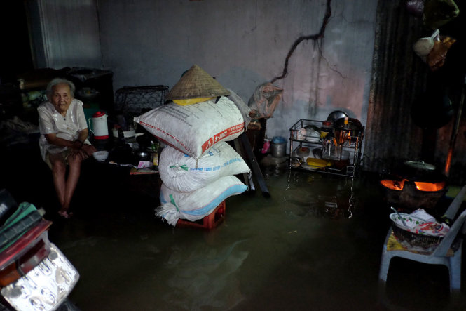 Căn nhà của bà Sáu tại P. Tân Phú, Q7 bị ngập nước nên bà phải lội nước để nấu cơm tối - Ảnh: HỮU THUẬN