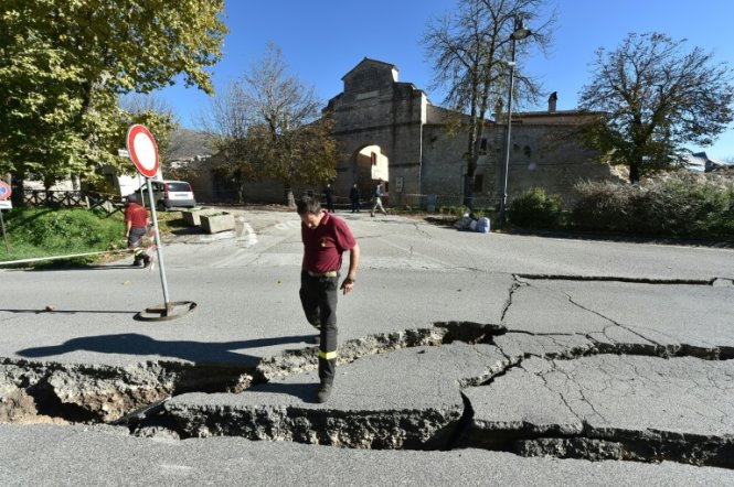 Lính cứu hỏa đứng tại một con đường bị hư hại sau trận động đất 6,6 độ richter tại Norcia - Ảnh: AFP