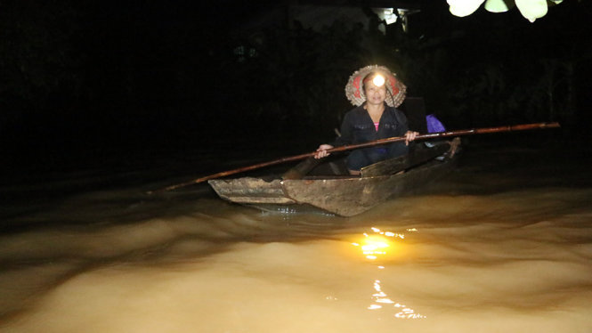 Bà Hoàng Thị Tường, 48 tuổi vội vả chèo thuyền về trong nước lũ chảy xiết để thu dọn tài sản - Ảnh: VĂN ĐỊNH