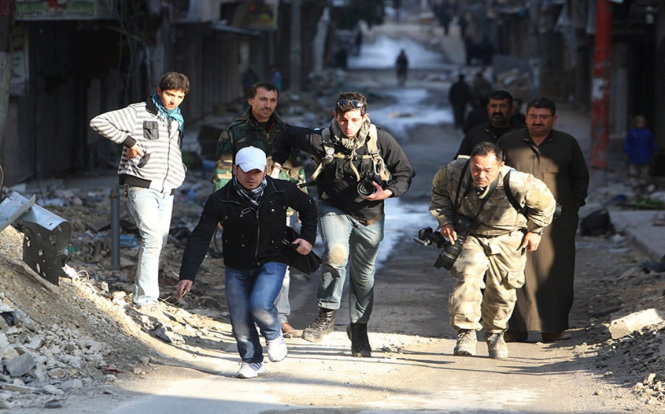 Các nhà báo mạo hiểm băng qua một con đường trong thành phố đang có chiến sự Aleppo ở Syria năm 2012 - Ảnh: Reuters
