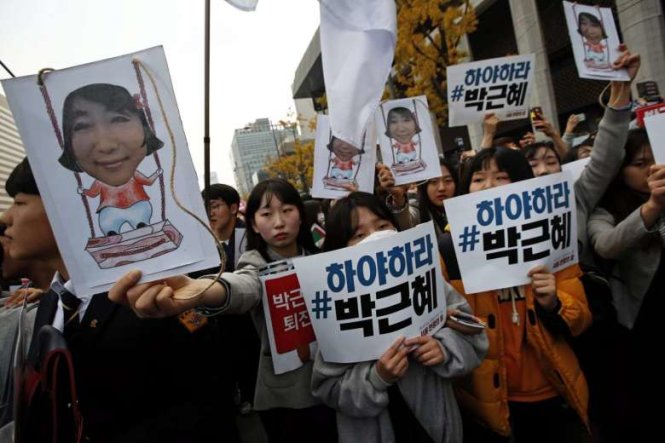 Người biểu tình cầm hình bà Choi Soon Sil và biểu ngữ yêu cầu tổng thống từ chức - Ảnh: EPA