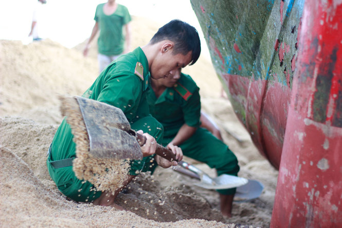 Lực lượng BĐBP tỉnh Khánh Hòa tiến hành đào cát bên hông mạn thuyền để “giải cứu” tàu gặp nạn - Ảnh: THANH TRÚC