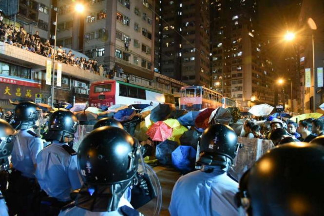 Người biểu tình giương dù chống đỡ lực lượng cảnh sát - Ảnh: Reuters