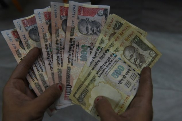 Một người dân cầm những tờ bạc mệnh giá 500 và 1.000 rupee ở thủ đô New Delhi, Ấn Độ - Ảnh: AFP