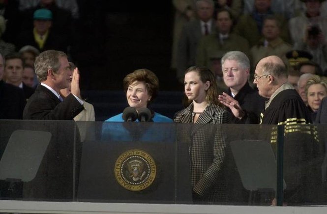 Tổng thống George W. Bush takes the oath of office from Chief Justice William Rehnquist to become the 43rd President of the United States, Saturday, Jan. 20, 2001, in Washington. Bush's wife Laura, wearing blue, and daughter Barbara look on.