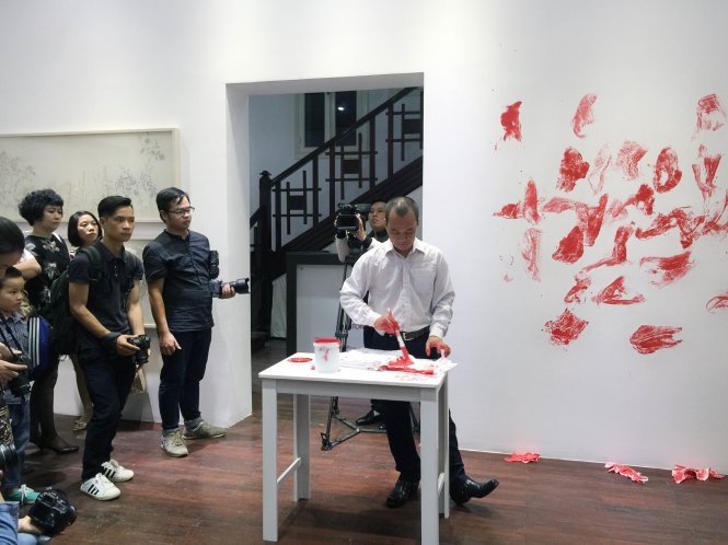 Nghệ sĩ Nguyễn Trí Mạnh trình diễn thực hiện tác phẩm thị giác ngay tại khai mạc triển lãm - Ảnh: DANH ANH