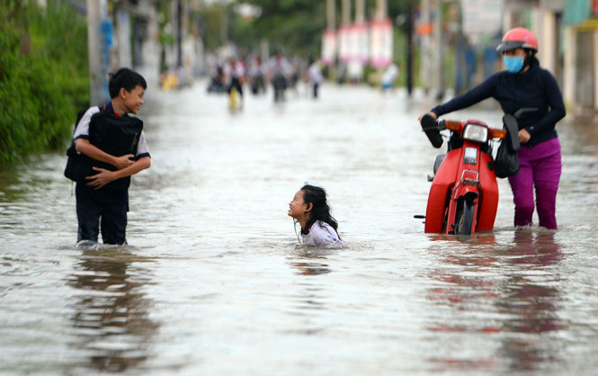 Một học sinh té ngã giữa dòng nước trên đường Lê Văn Lương - Ảnh: HỮU KHOA