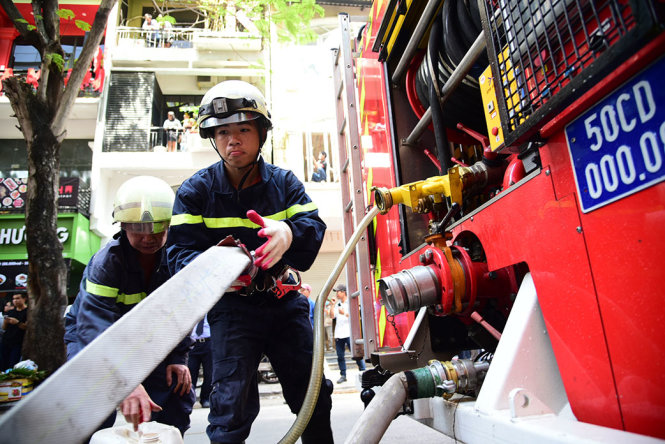 Cảnh sát PCCC lắp bơm nước để dử lý đám cháy - Ảnh: HỮU THUẬN