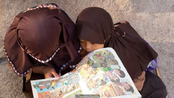 Những đứa trẻ say sưa bên cuốn truyện tranh mà anh Alimuddin mang tới cho chúng - Ảnh: BBC
