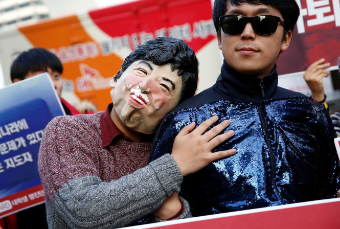 Một người đàn ông đeo mặt nạ mô tả diện mạo bà Park Geun-hye trong cuộc biểu tình - Ảnh: Reuters