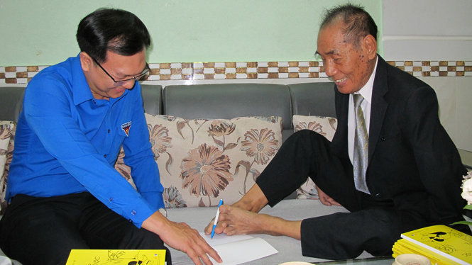 Nhà giáo ưu tú Nguyễn Ngọc Ký viết và ký tên tặng sách cho anh Lâm Đình Thắng, phó bí thư thường trực Thành đoàn TP.HCM và các bạn trẻ đến thăm chiều 19-11 - Ảnh: K.ANH