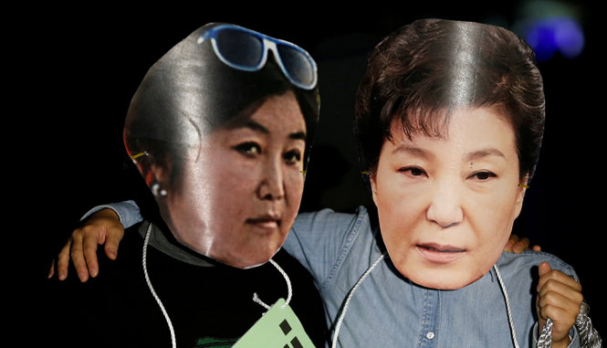 Những người biểu tình đeo mặt nạ hình tổng thống Park Geun Hye (phải) và bạn thân Choi Soon Sil - Ảnh: Reuters